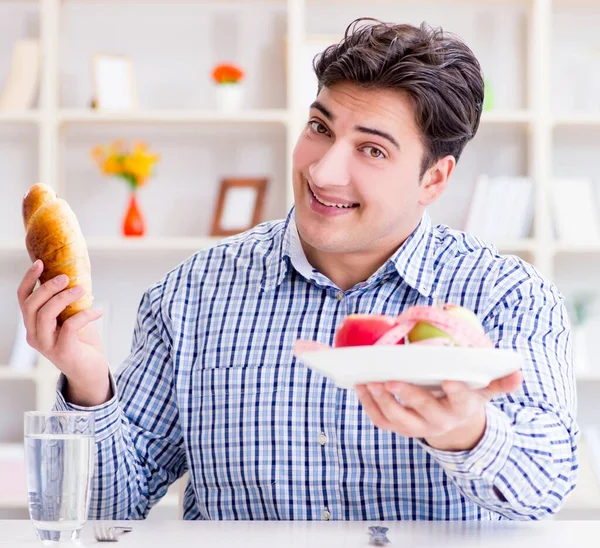 El hombre tiene un dilema entre la comida sana y el pan en la dieta con — Foto de Stock