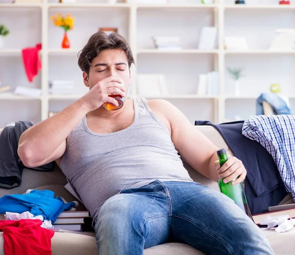 Jovem estudante bêbado beber álcool em um quarto bagunçado — Fotografia de Stock