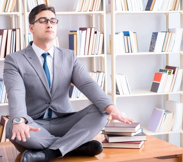 Businessman student in lotus position concentrating in the libr — Stock Photo, Image