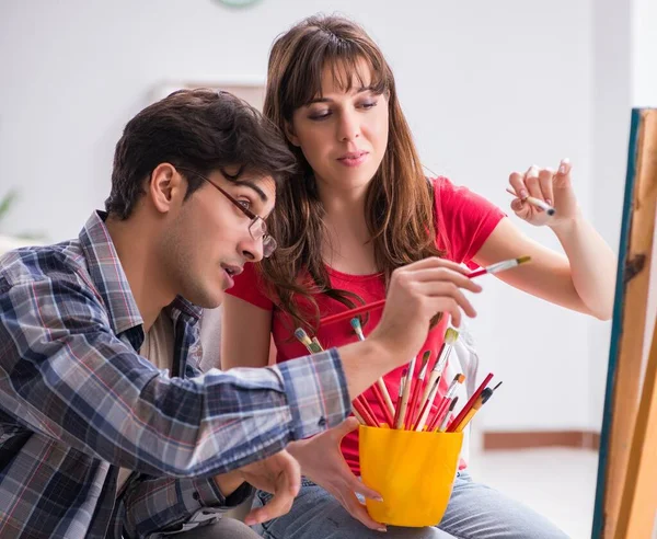 The artist coaching student in painting class in studio