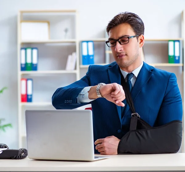 Businessman with broken arm working in office — Stock Photo, Image