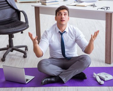 Adam stresle baş etmek için ofiste meditasyon yapıyor.