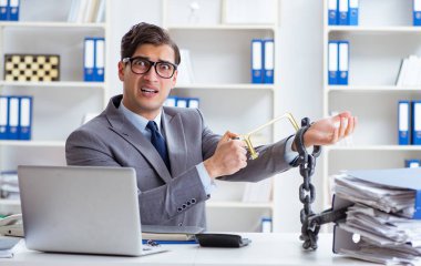 Ofis masasına zincirlenmiş meşgul bir çalışan.