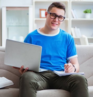 Sınavlara hazırlanan genç öğrenci kanepede ders çalışıyor.