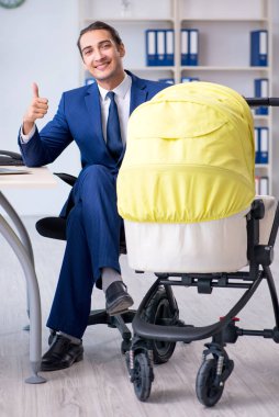 Genç baba ofiste yeni doğan bebeğe bakıyor.