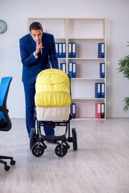 Genç baba ofiste yeni doğan bebeğe bakıyor.