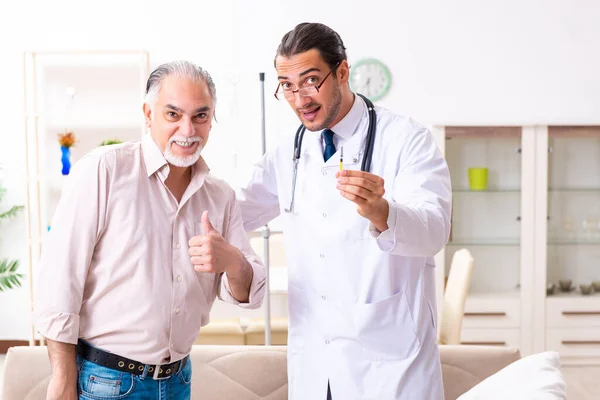 Joven médico varón visitando a paciente viejo en casa — Foto de Stock