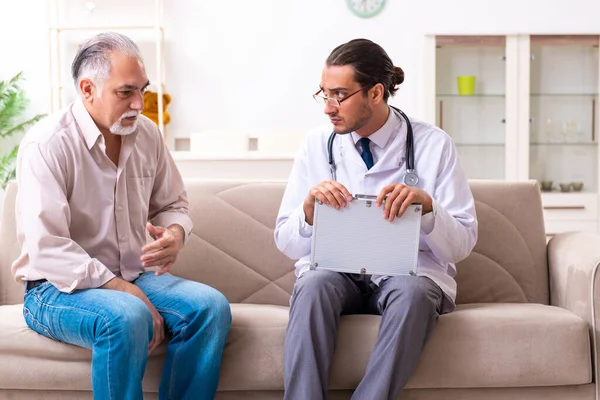 Young male doctor visiting old patient at home Royalty Free Stock Images
