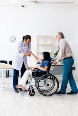 Yaşlı çift genç erkek doktoru ziyaret ediyor.