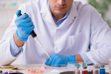 Uyuşturucu sentezi konseptinde genç erkek laboratuvar asistanı