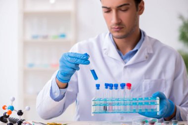 Uyuşturucu sentezi konseptinde genç erkek laboratuvar asistanı
