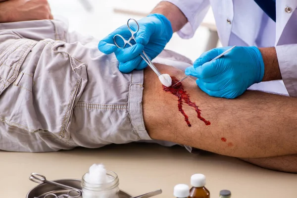 Homem ferido na perna visitando o velho médico no conceito de primeiros socorros — Fotografia de Stock