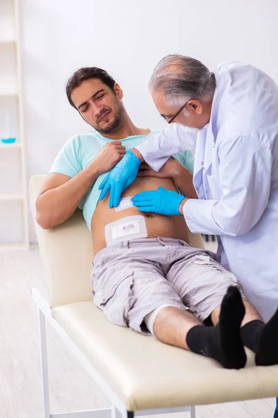 Injured young man visiting experienced male doctor — Stockfoto