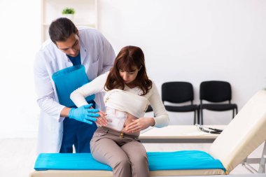 Yaralı genç kadın genç erkek doktoru ziyaret ediyor.