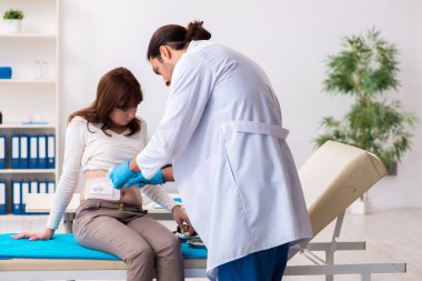 Yaralı genç kadın genç erkek doktoru ziyaret ediyor.