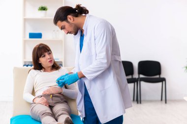 Yaralı genç kadın genç erkek doktoru ziyaret ediyor.