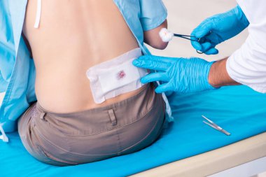 Yaralı genç kadın genç erkek doktoru ziyaret ediyor.