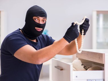 Soyguncu kar maskesi takıp değerli şeyler çalıyor.