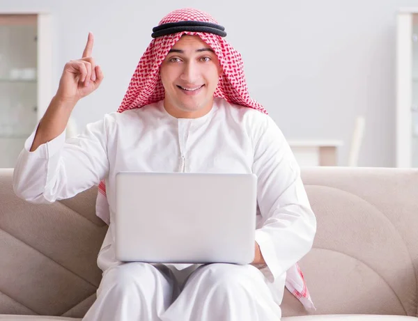 Hombre de negocios árabe joven que trabaja con el ordenador portátil en el sofá —  Fotos de Stock