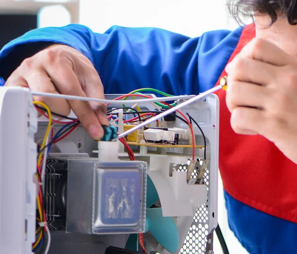 Genç tamirci mikrodalga fırını tamir ediyor. — Stok fotoğraf