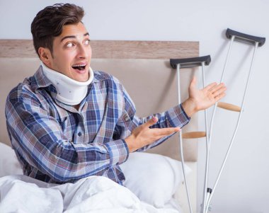 Koltuk değnekleriyle yataktaki yaralı adam.