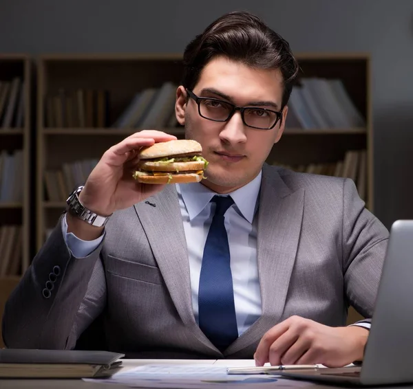 ビジネスマンは夜遅くハンバーガーを食べて — ストック写真