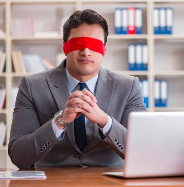 Ofiste masasında oturan gözü bağlı iş adamı.