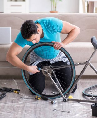 Evde bisiklet tamir eden genç bir adam.