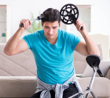 Evde bisiklet tamir eden genç bir adam.