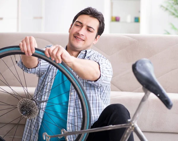 Evde bisiklet tamir eden genç bir adam.