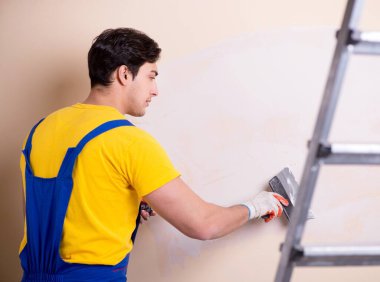 Duvara alçı yapıştıran genç müteahhit.