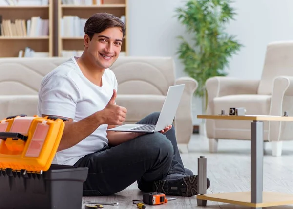 Adam evde mobilya montajı yapıyor.