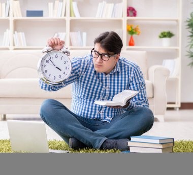 Genç yakışıklı adam evde yerde oturuyor.