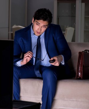 İşadamı gece geç saatte televizyon izliyor.