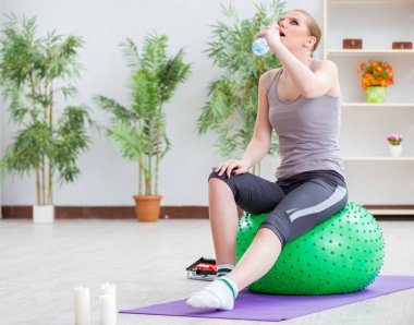 Spor salonunda denge topuyla egzersiz yapan genç bir kadın.