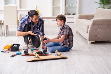 Genç baba oğluyla kaykay tamir ediyor.