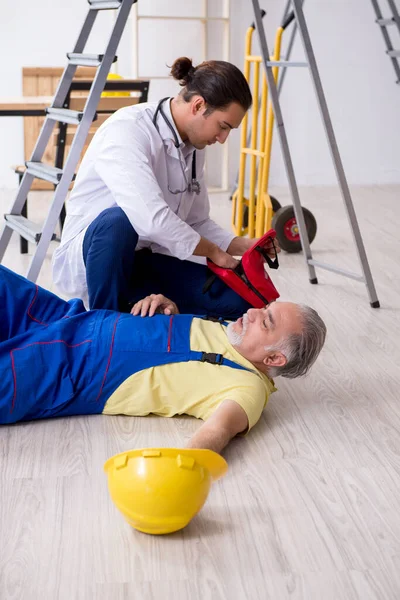 Giovane medico di sesso maschile e vecchio appaltatore nel concetto di pronto soccorso — Foto Stock