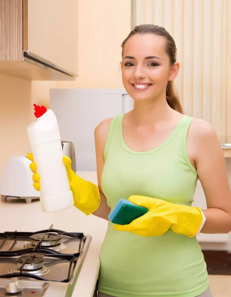 Junge Frau putzt Küche mit Flasche — Stockfoto