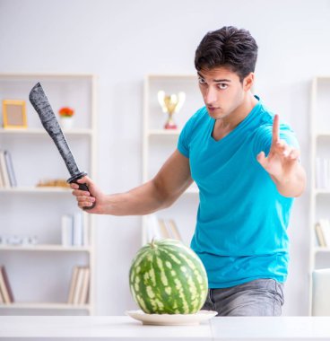 Evde karpuz yiyen bir adam.