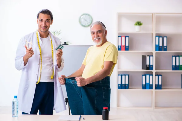 Doctor dietician and happy patient wearing large trousers — Stock Photo, Image