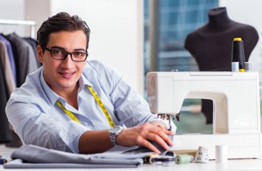 Genç terzi yeni elbiseler üzerinde çalışıyor.