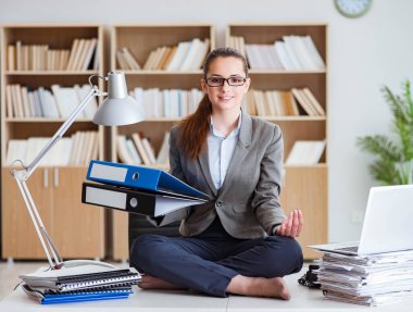 İş kadını ofiste meditasyon yapıyor.