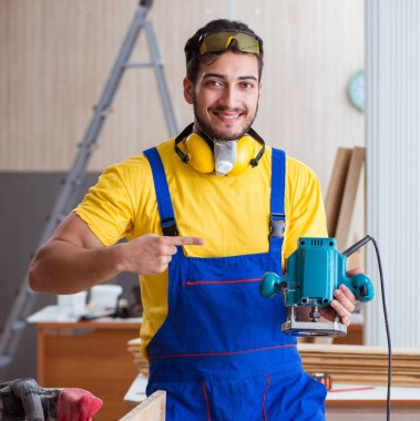 Elektrikli aletlerle çalışan genç marangoz.