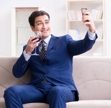 İş adamı evde oturmuş şarap içiyor.