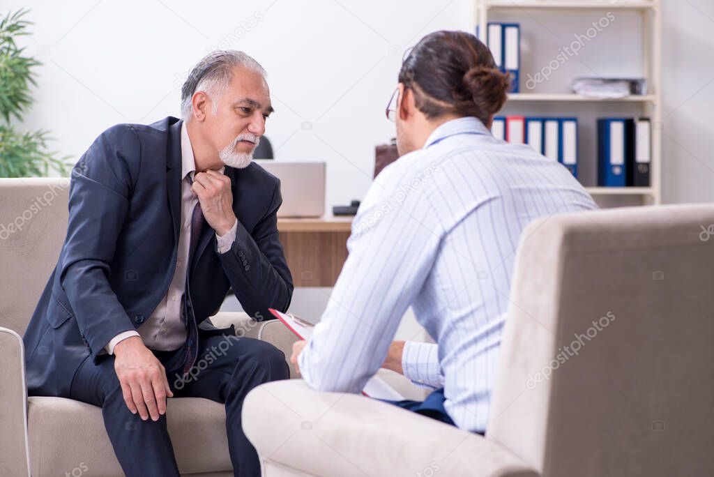 Old man visiting young male doctor psychologist