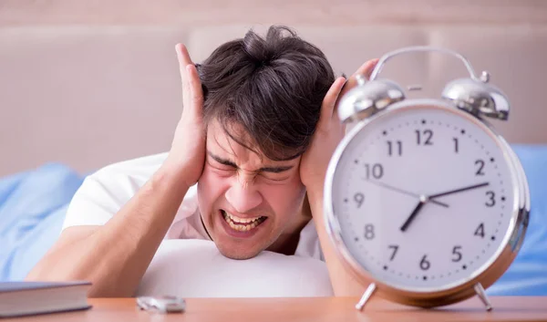 Homme au lit frustré souffrant d'insomnie avec un cloc d'alarme — Photo