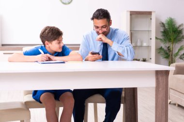 Baba oğlunun sınava hazırlanmasına yardım ediyor.