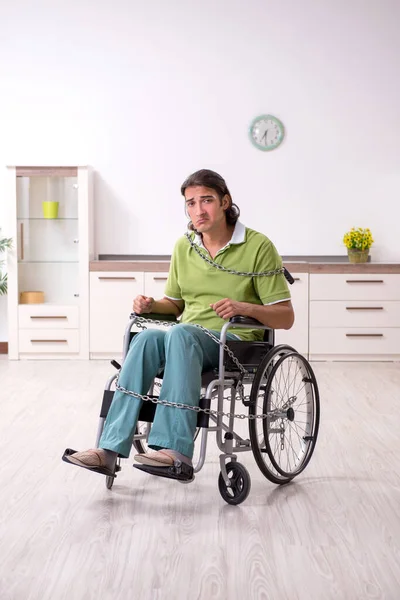 Mladý muž invalidní v invalidním vozíku trpí doma — Stock fotografie