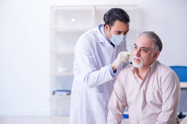 Erkek hasta doktor otolaryngologu ziyaret ediyor.