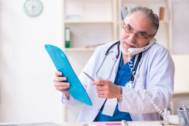 Klinikte çalışan yaşlı erkek doktor.